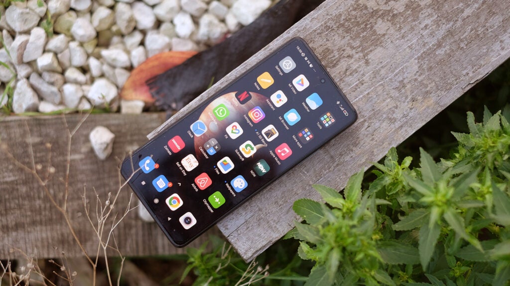 Xiaomi 11T Pro smartphone resting on a wooden plank outdoors.