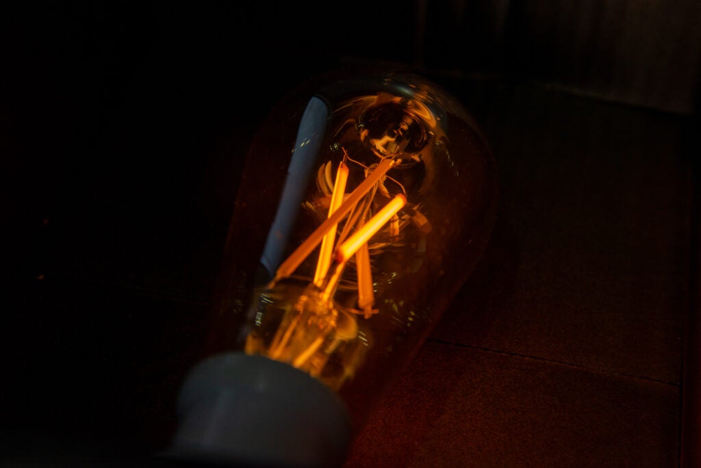 Illuminated WiZ smart LED light bulb on dark background.Illuminated WiZ smart LED light bulb close-up.