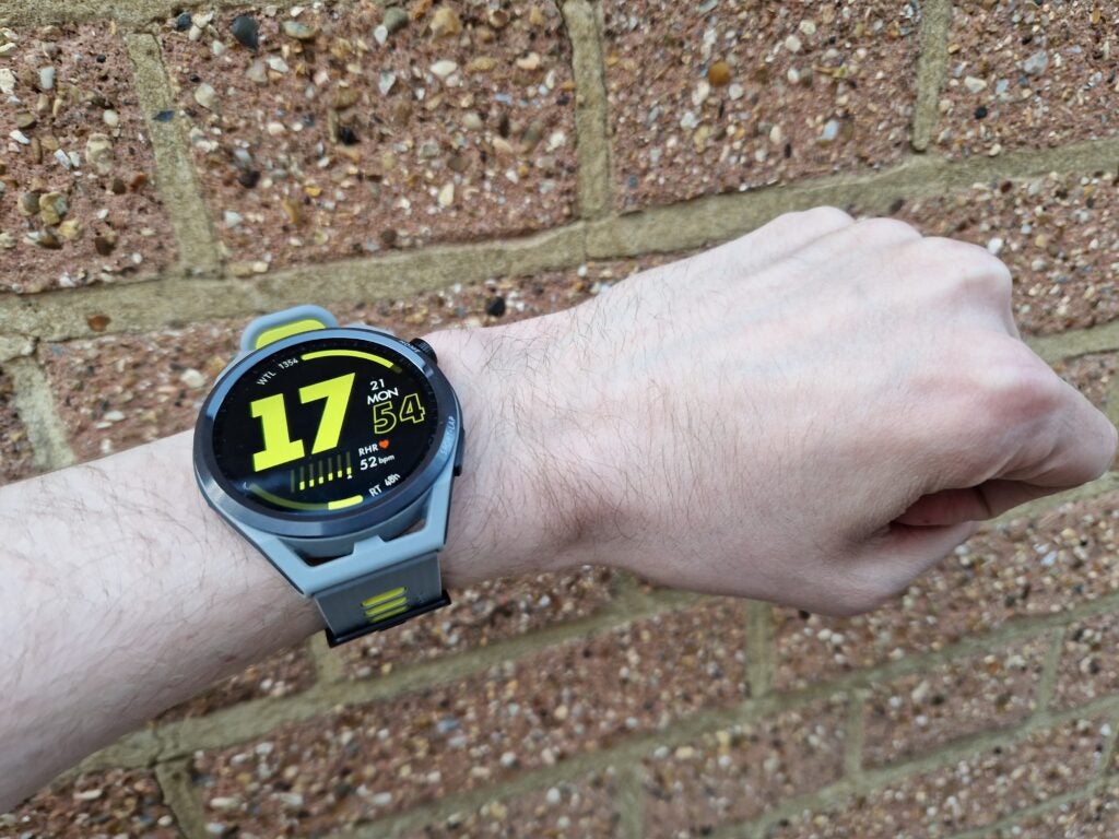Huawei Watch GT Runner home screen in front of brick wall