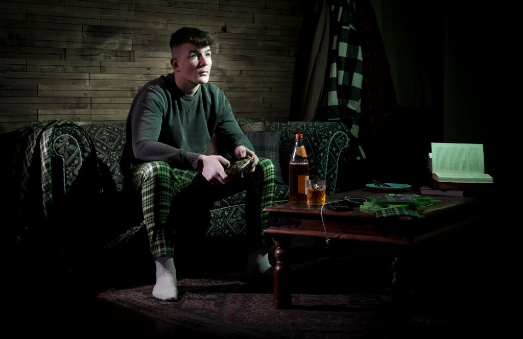 Man sat with Xbox controller in a world of tartan thanks to Scotland