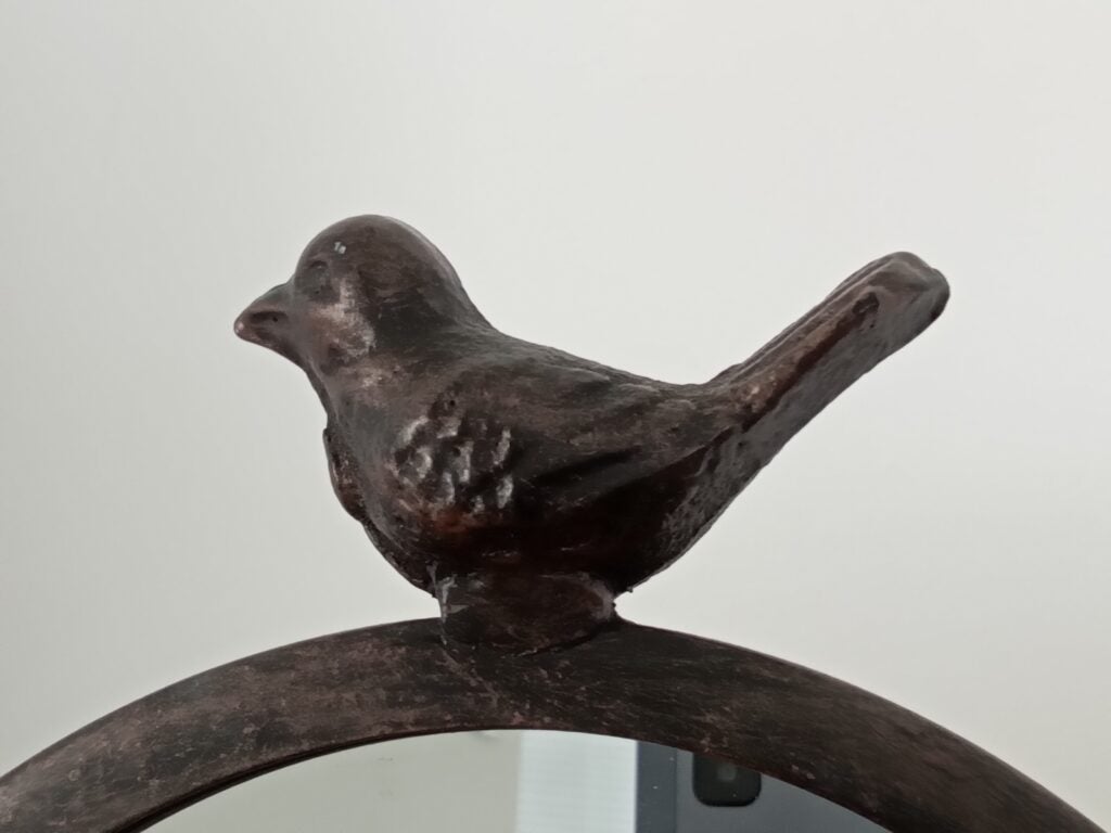 Metal bird sculpture on a circular stand.