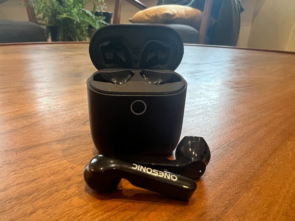 The OneSonic earbuds on a table with the charging case open