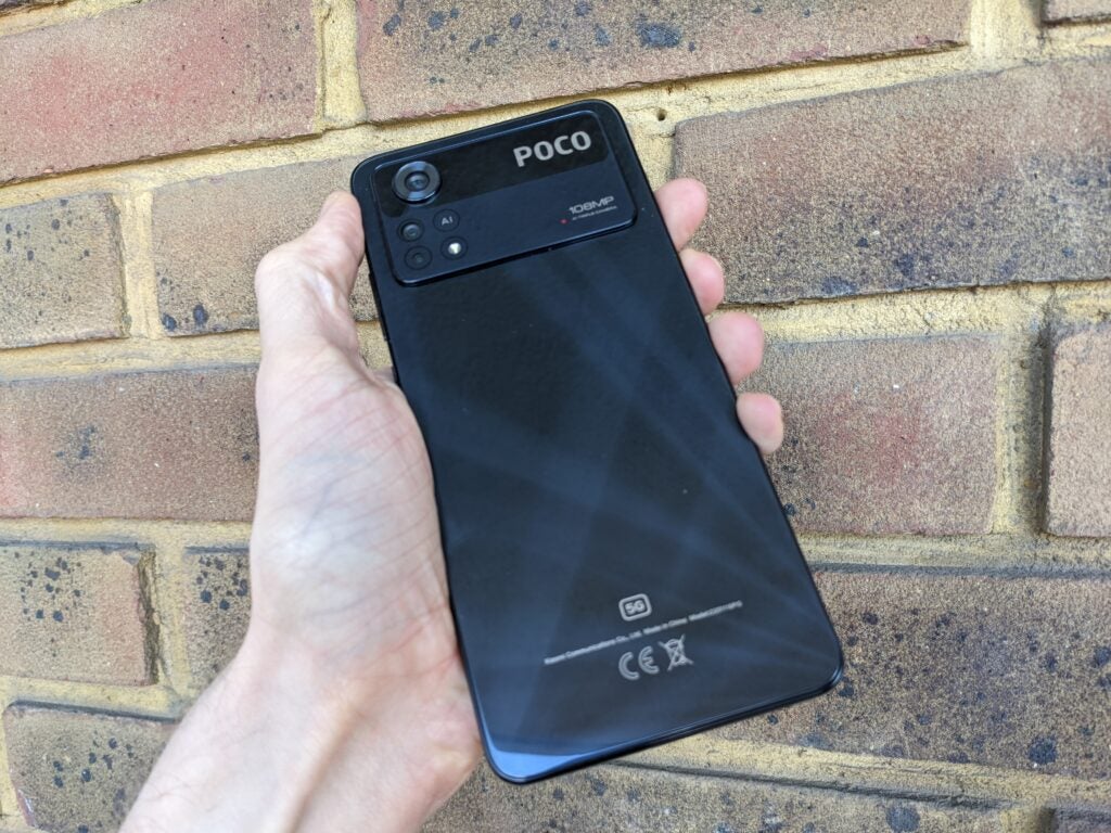Poco X4 Pro 5G rear panel, held in front of a wall
