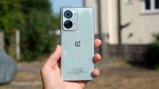 Hand holding OnePlus Nord 2T smartphone with rear camera visible.