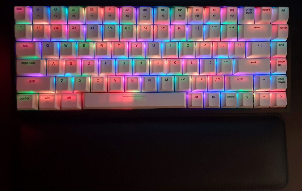 The Vissles V84 and wrist rest, RGB sparkles turned on, in a dim room