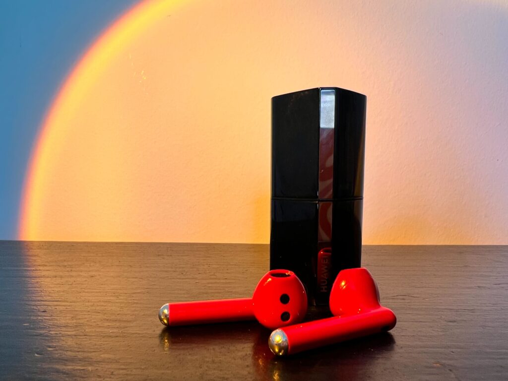 The Freebud Lipstick earbuds in red sat next to the charging case
