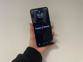 The Poco M5 being held up with the TR background