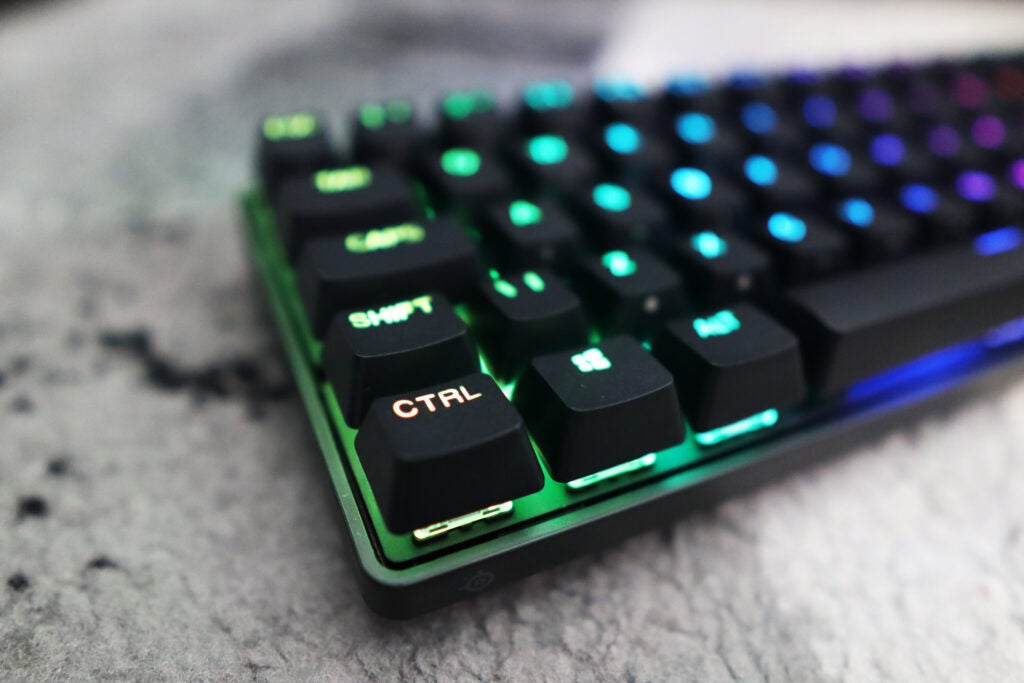 Bottom left corner close-up of the lit-up Apex Pro Mini Wireless keyboard