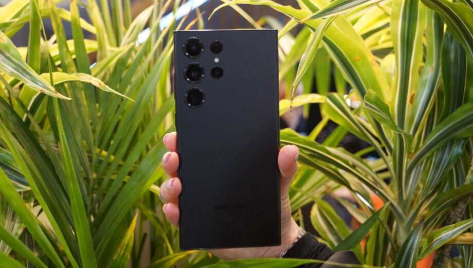 Holding a Samsung Galaxy S23 Ultra in-hand with plants in the background