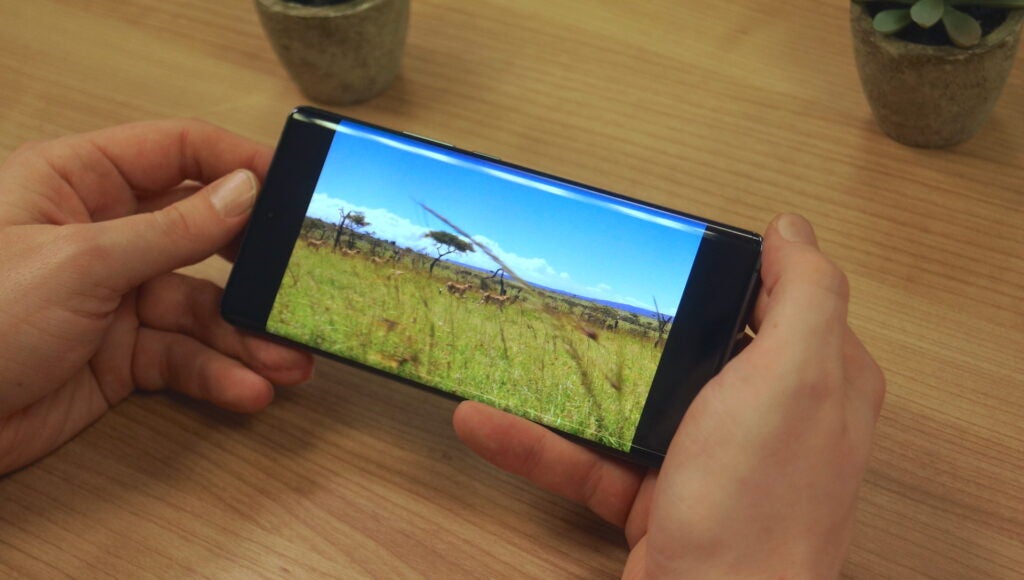 Vivo X90 Pro displaying landscape photo on screen.