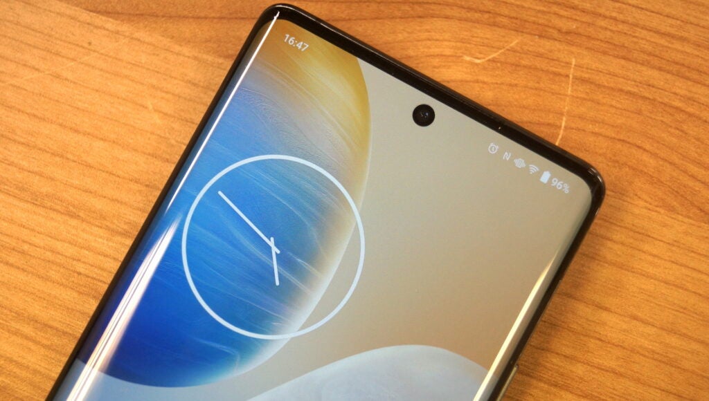 Vivo X90 Pro smartphone displaying clock wallpaper on screen.