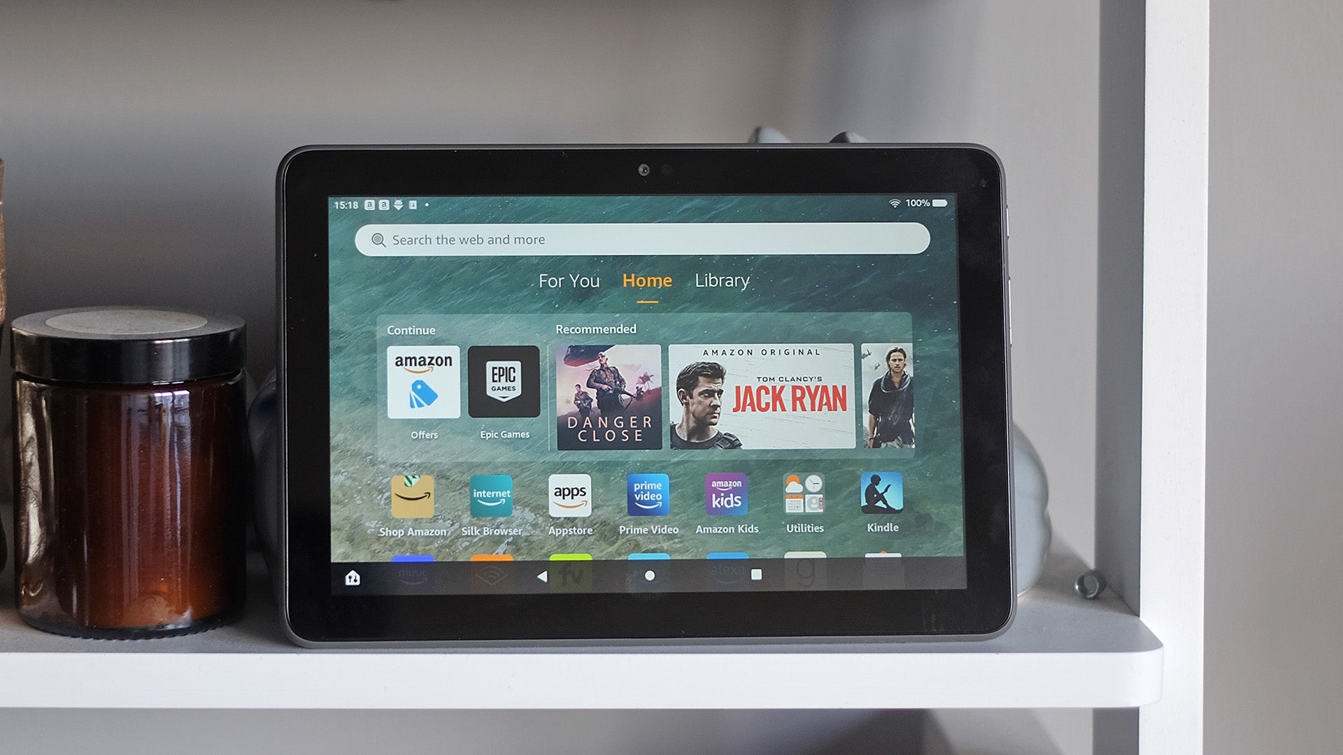 Amazon Fire HD 8 Plus tablet displaying home screen on shelf.