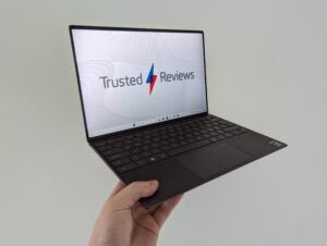 Dell XPS 13 laptop held in hand with on-screen review.
