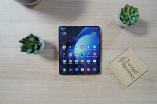 Samsung Galaxy Z Fold 5 on a desk with plants and review plaque.