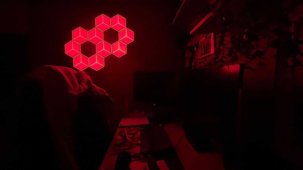 10 Govee Glide Hexagon Light Panels Ultra being used in the dark as a nightlight.Govee Glide Hexagon Light Panels illuminating room in red.