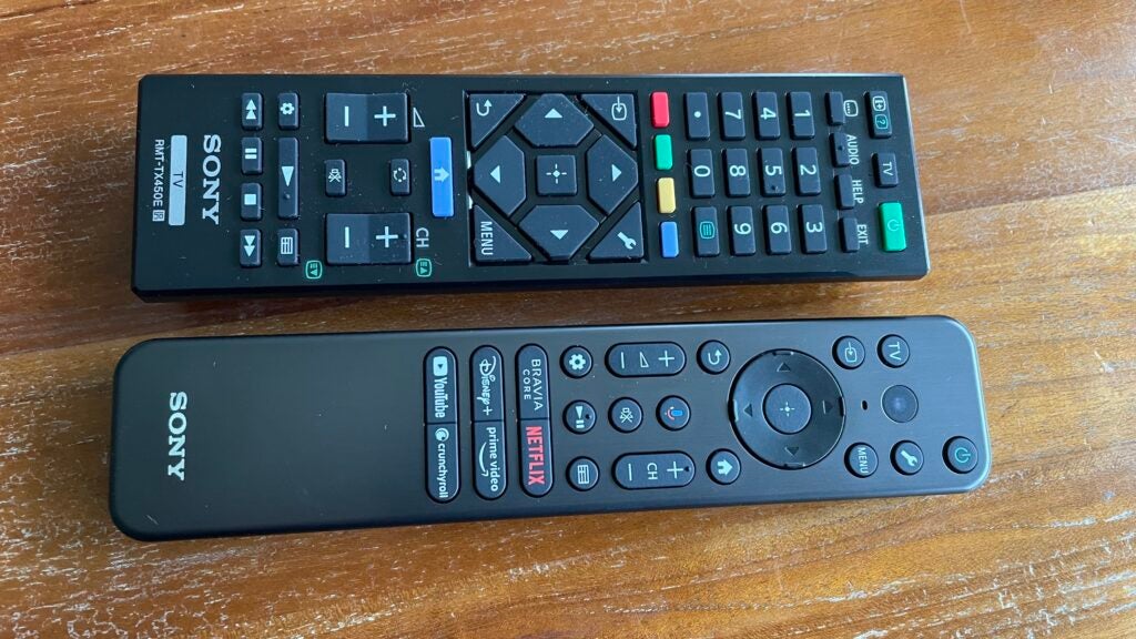 Close up of the two remote controls you get with the Sony 65X95L TV.Two Sony TV remotes on a wooden table.