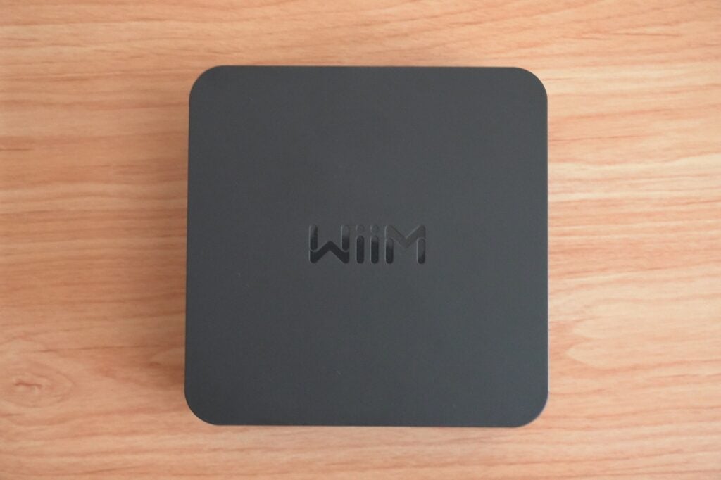 Wiim Pro top down view v2WiiM Pro streaming device on wooden surface.