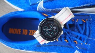 Coros Pace 3 smartwatch on a blue running shoe displaying time and stats.