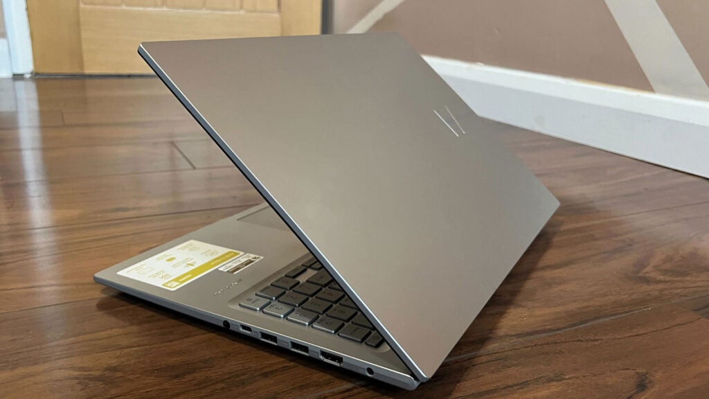 An angled view of the Asus Vivobook 16 showing the lid partially closed with the I/O array in view.