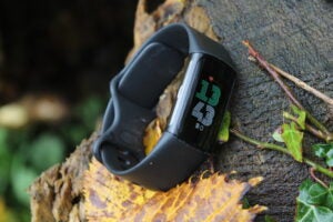 Fitbit Charge 6 on a tree stump showing heart rate.
