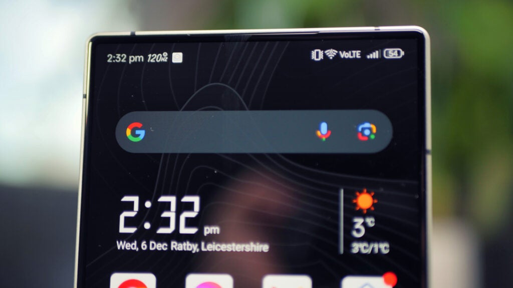 Hidden selfie camera in the RedMagic 9 ProRedMagic 9 Pro smartphone showing time and weather on screen.Person taking a selfie with a blurred background.