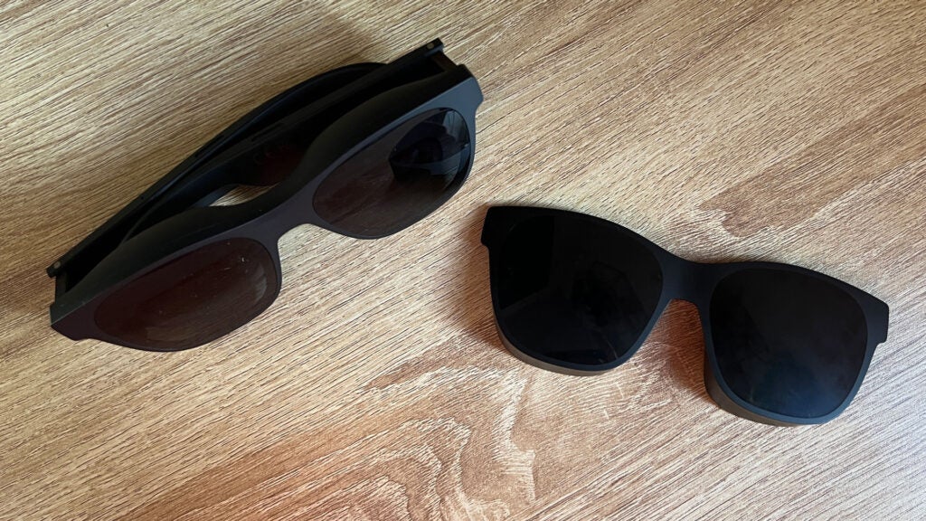 The XReal Air 2 Pro glasses and attachable blackout shade.Two pairs of sunglasses on a wooden surface.