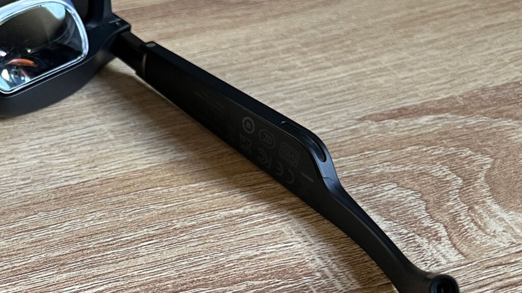 A close-up of the Xreal Air 2 Pro glasses showing one of the speakers on the underside of the temple arm.Close-up of Xreal Air 2 Pro smart glasses' arm with controls.