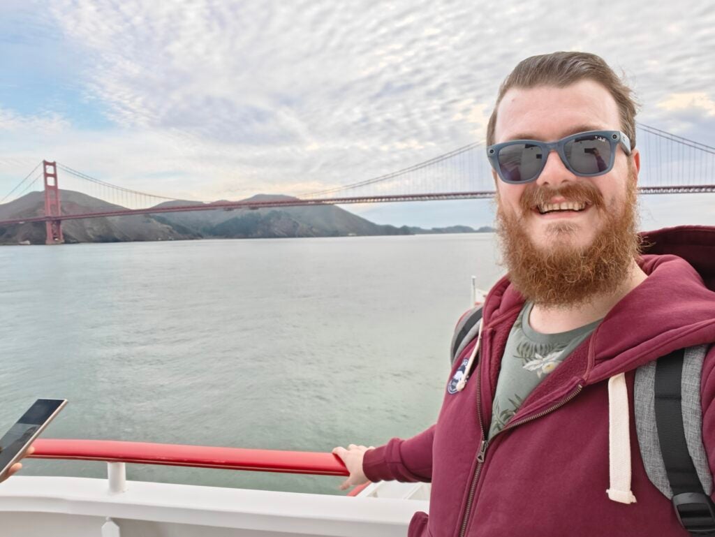 OnePlus 12 selfie camera sampleMan with beard taking selfie with Golden Gate Bridge background.