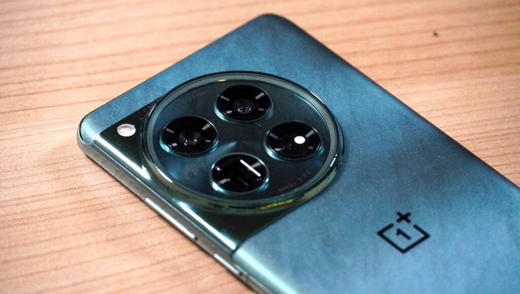 OnePlus 12 camera bumpOnePlus smartphone with circular camera module on wooden surface.