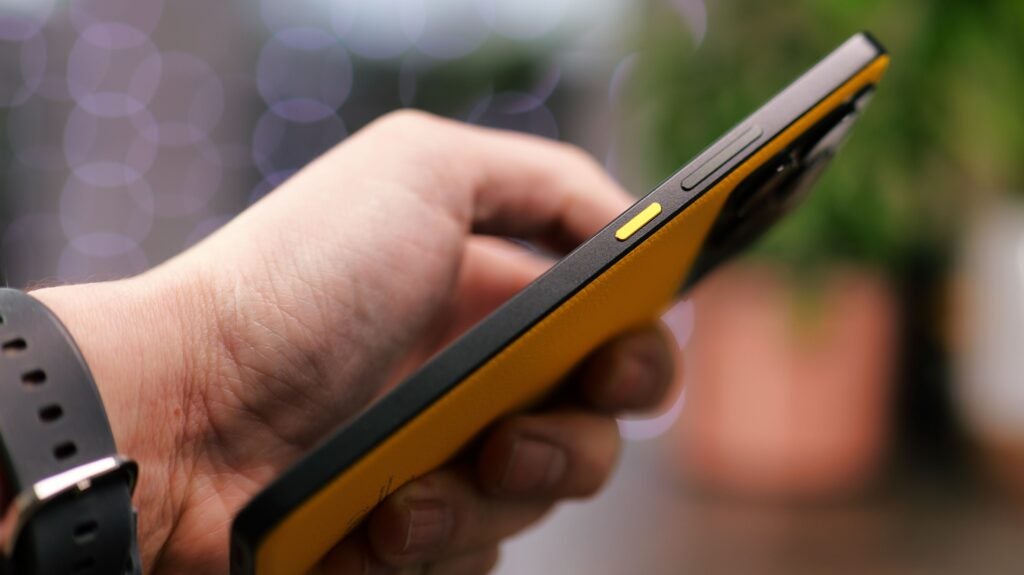 Poco X6 Pro side-onHand holding a yellow Poco X6 Pro smartphone.