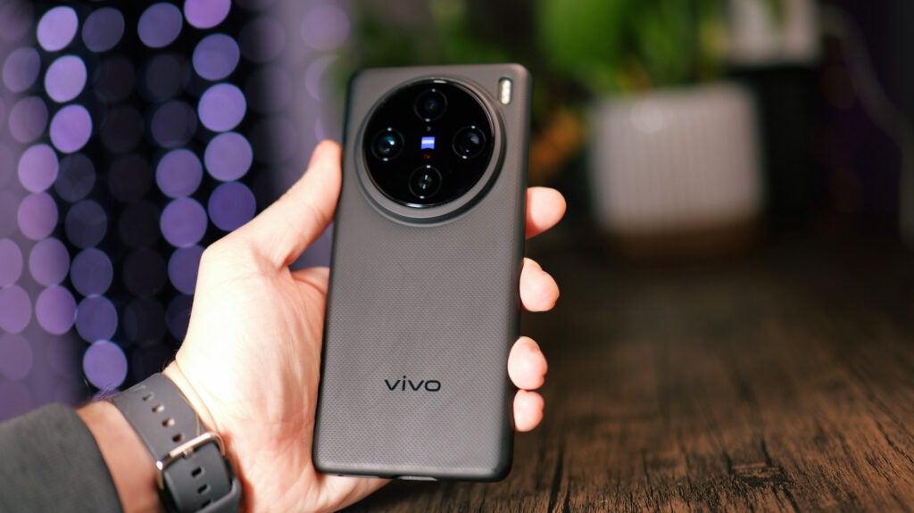 Vivo X100 Pro in-handHand holding Vivo X100 Pro smartphone with camera detail.