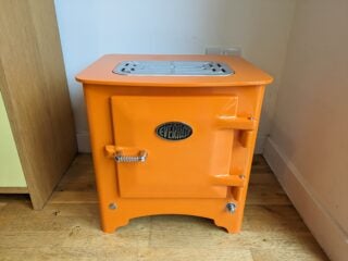 Front, top view of the stove in bright orange