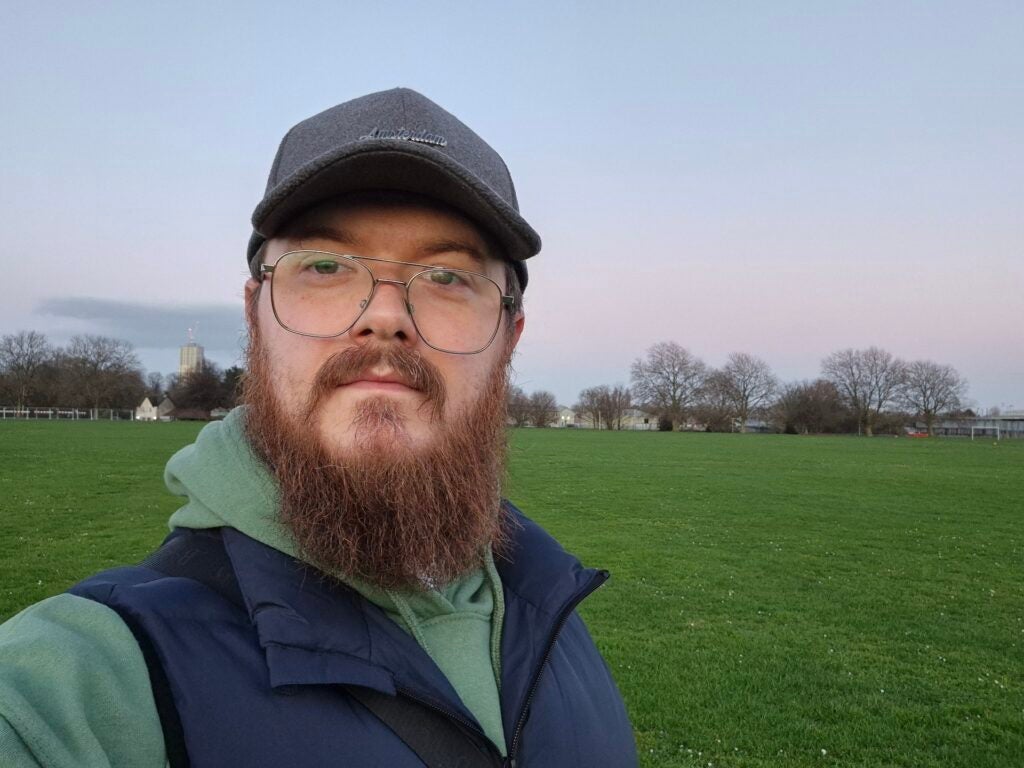 Samsung Galaxy S24 Plus selfie camera sampleMan taking a selfie in a park at twilight.