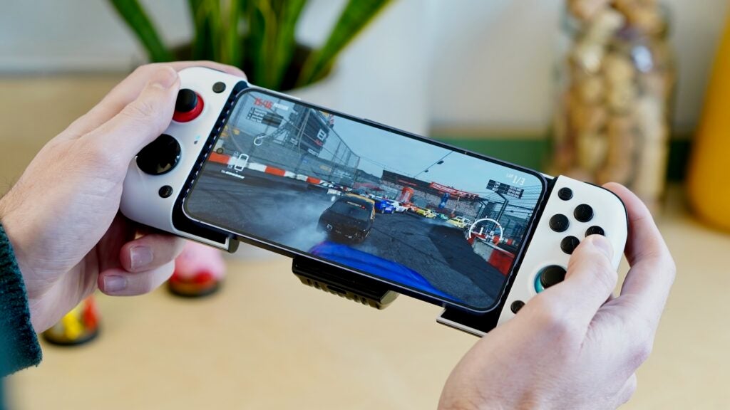 GameSir X3 in-handHands holding GameSir X3 controller attached to smartphone with racing game.Hands holding GameSir X3 attached to a smartphone playing a racing game.