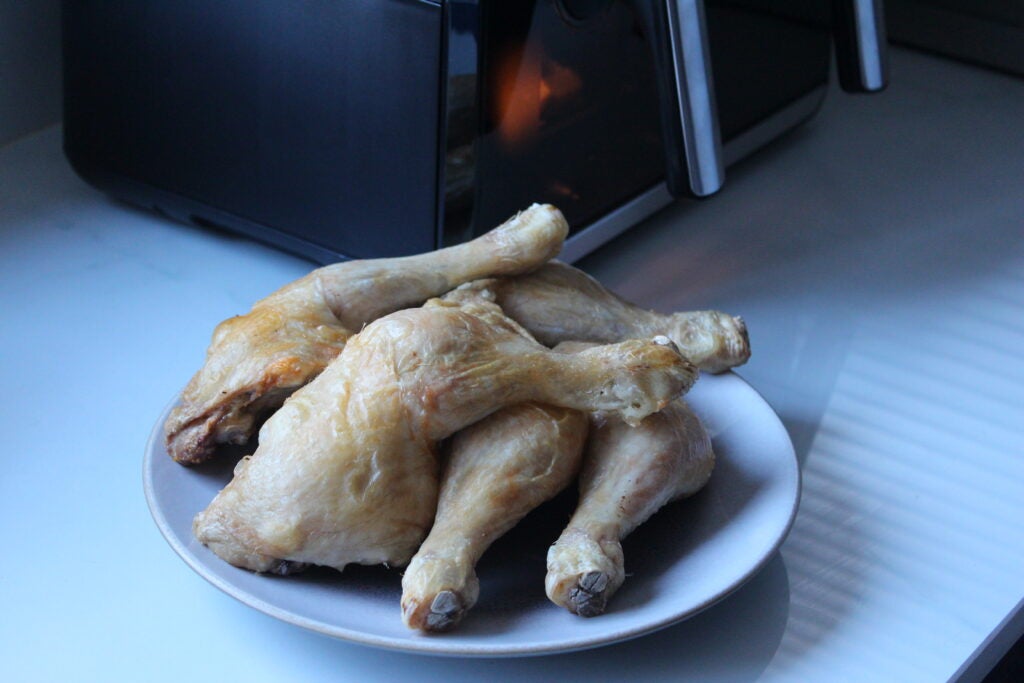 Salter Fuzion Dual Air Fryer cooked chickenCooked chicken drumsticks on plate with Salter Air Fryer in background.